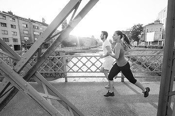 Image showing young couple jogging across the bridge in the city