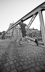 Image showing man jogging across the bridge at sunny morning