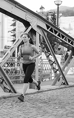 Image showing woman jogging across the bridge at sunny morning