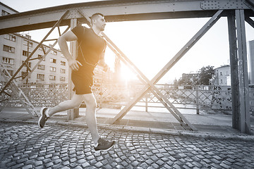 Image showing man jogging across the bridge at sunny morning