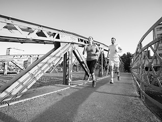 Image showing young couple jogging across the bridge in the city