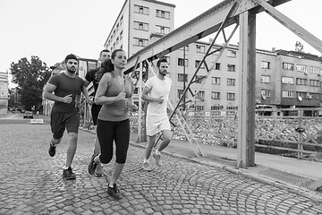 Image showing group of young people jogging across the bridge