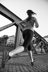 Image showing woman jogging across the bridge at sunny morning