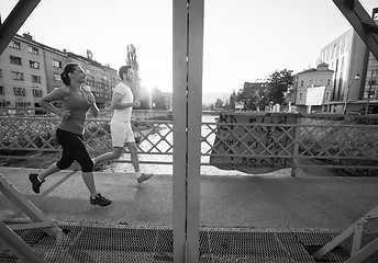 Image showing young couple jogging across the bridge in the city