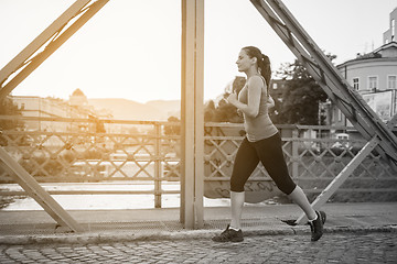 Image showing woman jogging across the bridge at sunny morning