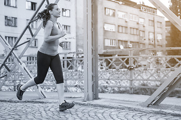 Image showing woman jogging across the bridge at sunny morning