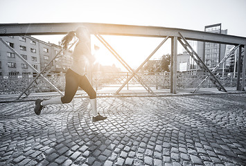 Image showing woman jogging across the bridge at sunny morning