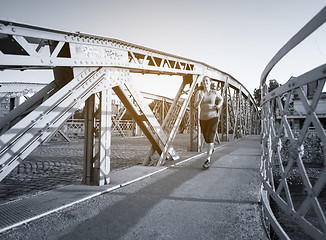 Image showing woman jogging across the bridge at sunny morning