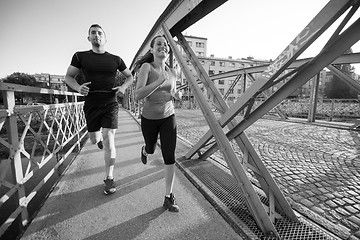 Image showing young couple jogging across the bridge in the city