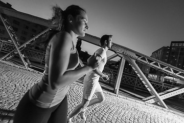 Image showing couple jogging across the bridge in the city