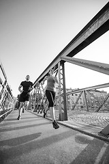 Image showing young couple jogging across the bridge in the city