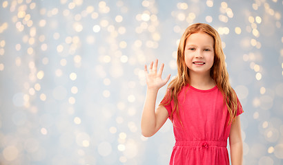 Image showing smiling red haired girl waving hand over lights