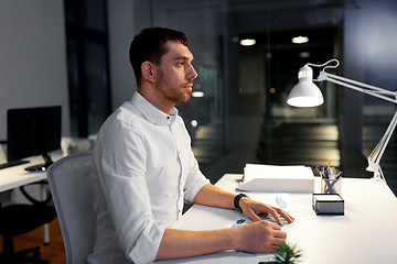 Image showing businessman sitting at table at night office