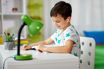 Image showing student boy in earphones reading book at home