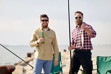 Image showing happy friends with fishing rods and beer on pier