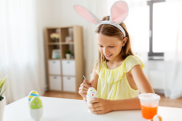 Image showing happy girl coloring easter eggs at home