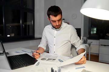 Image showing businessman with papers and laptop at night office