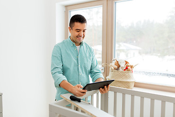 Image showing father with tablet pc assembling baby bed at home