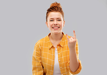 Image showing happy red haired teenage girl showing rock gesture