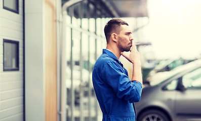 Image showing auto mechanic smoking cigarette at car workshop