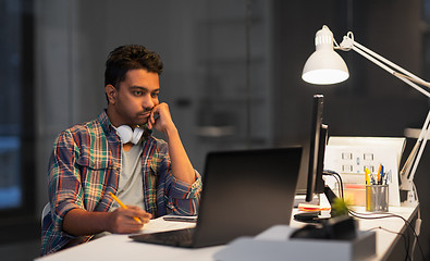 Image showing creative man with laptop working at night office