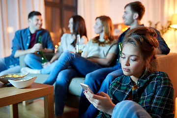 Image showing sad young woman with smartphone at home party