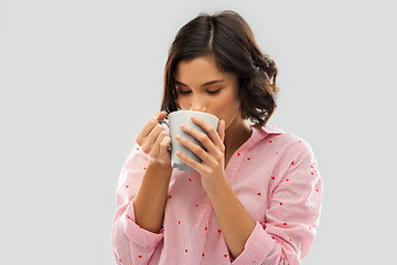 Image showing young woman in pajama drinking coffee from mug