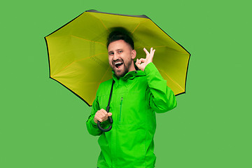 Image showing handsome bearded young man holding umbrella and looking at camera isolated on white