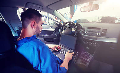 Image showing mechanic man with laptop making car diagnostic