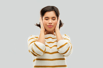 Image showing happy woman in pullover closing ears by hands