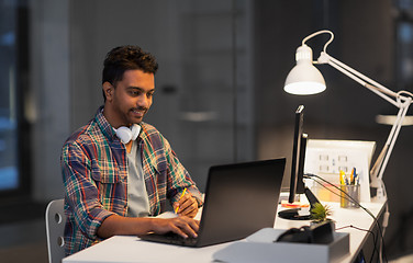 Image showing creative man with laptop working at night office