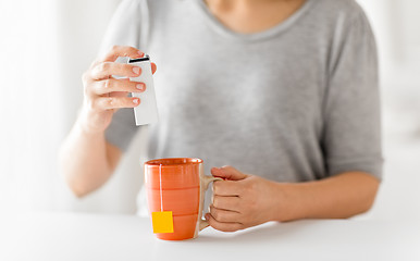 Image showing close up of woman adding sweetener to cup of tea