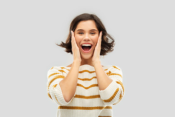 Image showing impressed woman in pullover holding to her face