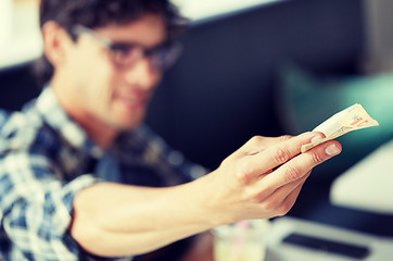 Image showing happy man with cash money paying at cafe