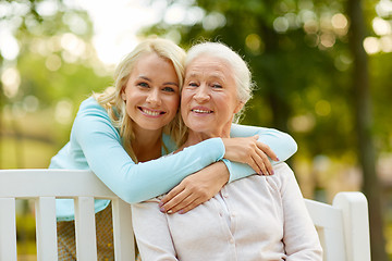 Image showing daughter with senior mother hugging on park bench