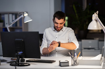 Image showing happy businessman with smart watch at nigh office