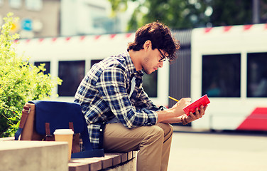 Image showing man with notebook or diary writing on city street