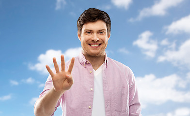 Image showing young man showing four fingers over sky