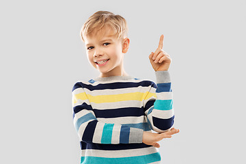 Image showing little boy in striped pullover pointing finger up