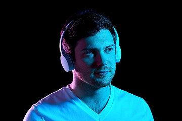 Image showing man in headphones over neon lights of night club