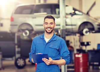 Image showing happy mechanic man with clipboard at car workshop