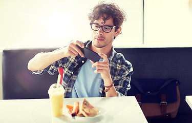 Image showing man with smartphone photographing food at cafe