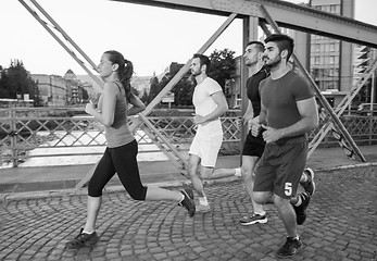 Image showing group of young people jogging across the bridge