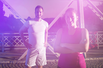 Image showing portrait of couple jogging across the bridge in the city