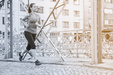 Image showing woman jogging across the bridge at sunny morning