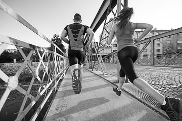 Image showing young couple jogging across the bridge in the city