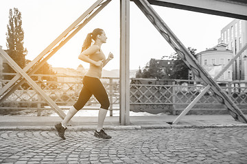 Image showing woman jogging across the bridge at sunny morning