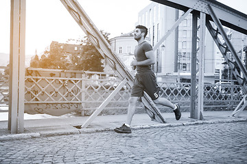 Image showing man jogging across the bridge at sunny morning