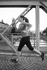 Image showing woman jogging across the bridge at sunny morning