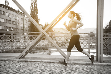 Image showing woman jogging across the bridge at sunny morning